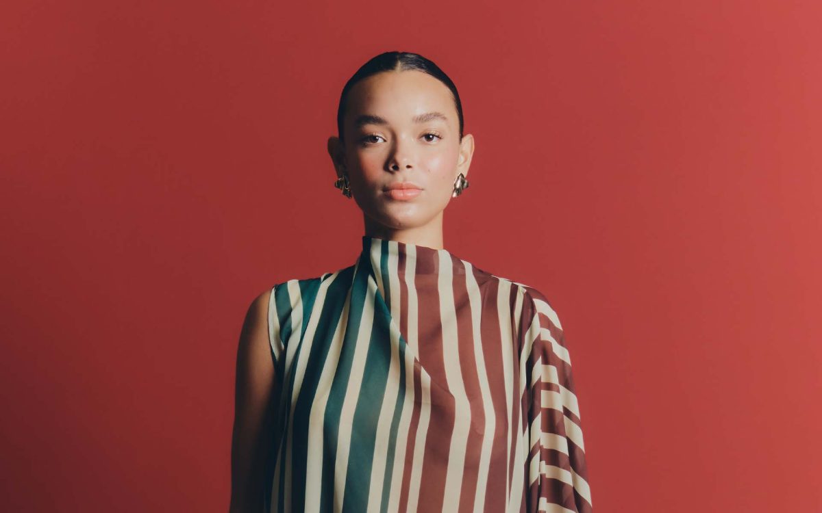 Modelo con vestido de rayas y fondo rojo, estilo moderno y elegante.