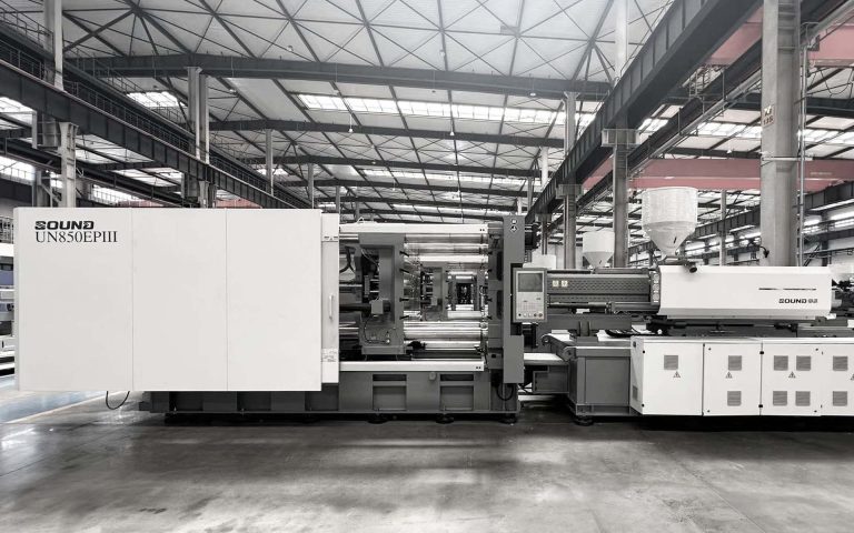 Máquina de moldeo por inyección en una fábrica moderna, bajo un techo industrial.