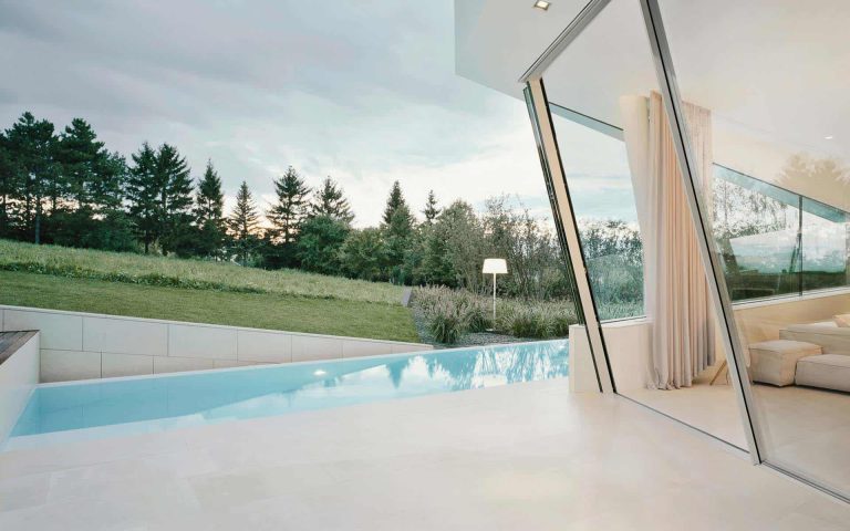 Vista moderna de una casa con piscina y jardín, destacando una arquitectura contemporánea y conexión con la naturaleza.