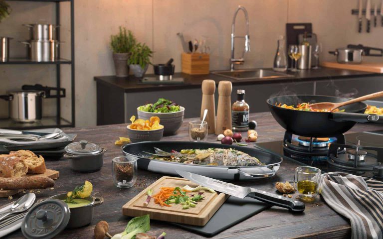 Mesa de cocina moderna con ingredientes frescos, utensilios y platos listos para preparar una deliciosa comida.