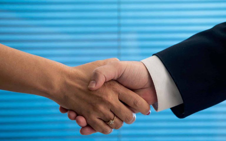 Apretón de manos entre dos personas, simbolizando un acuerdo o colaboración en un entorno profesional.