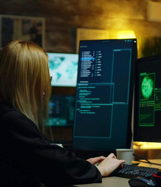 Mujer trabajando en múltiples pantallas, analizando datos en un entorno tecnológico moderno y profesional.