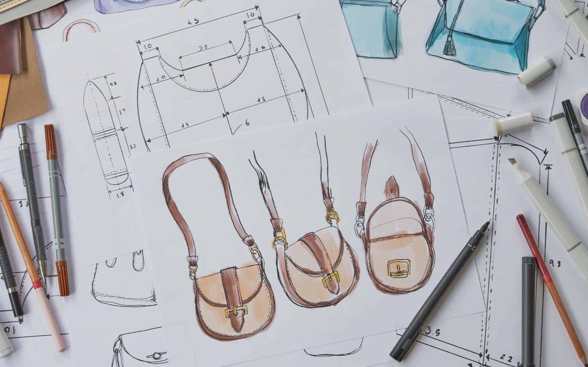 Esquemas de bolsos de diseño, con lápices y herramientas de dibujo sobre una mesa, en tonos suaves y detallados.